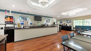 A spacious hotel lobby with a central counter, seating area, and a television mounted on the wall. - Best Western Post Oak Inn (Burnet)