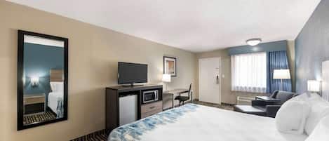 Una habitación de hotel con una cama, un escritorio, un televisor y un espejo.
