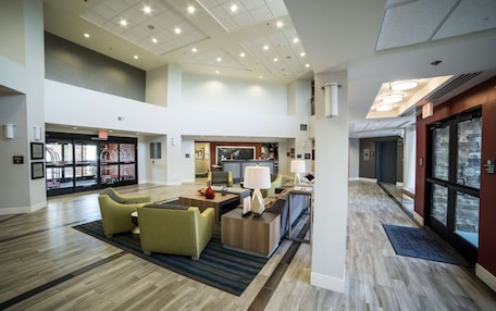 A spacious lobby with a high ceiling, modern lighting, and a central seating area with sofas and a coffee table.