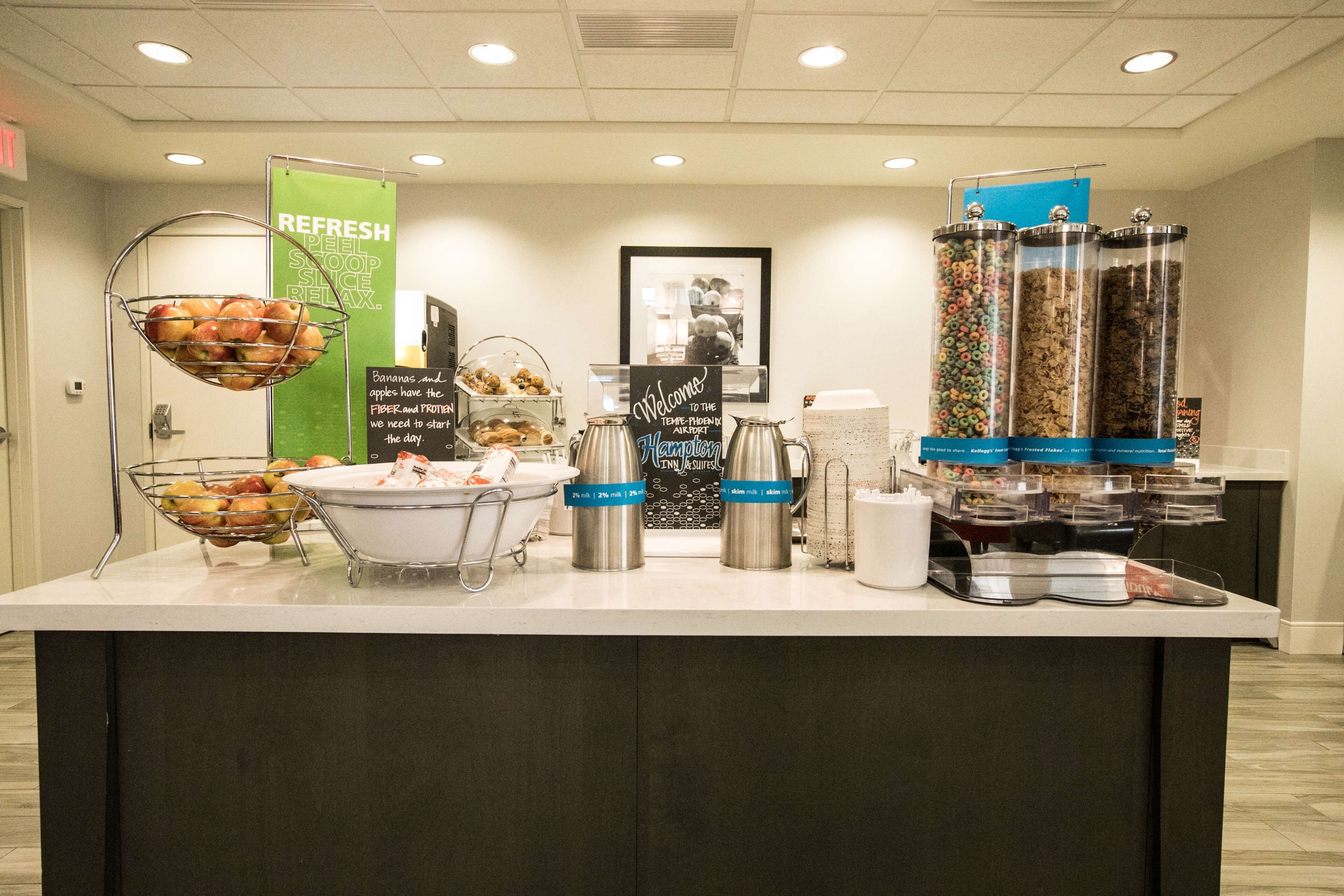 A buffet counter with various food items, including fruits, cereals, and beverages.