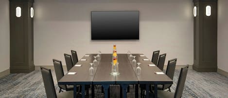 A conference room with a long table, chairs, a flat-screen TV, and a decorative item on the table.