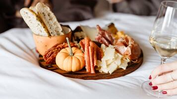 Une planche de charcuterie comprenant différentes sortes de viandes, de fromages et de pain, accompagnée d’un verre de vin blanc.