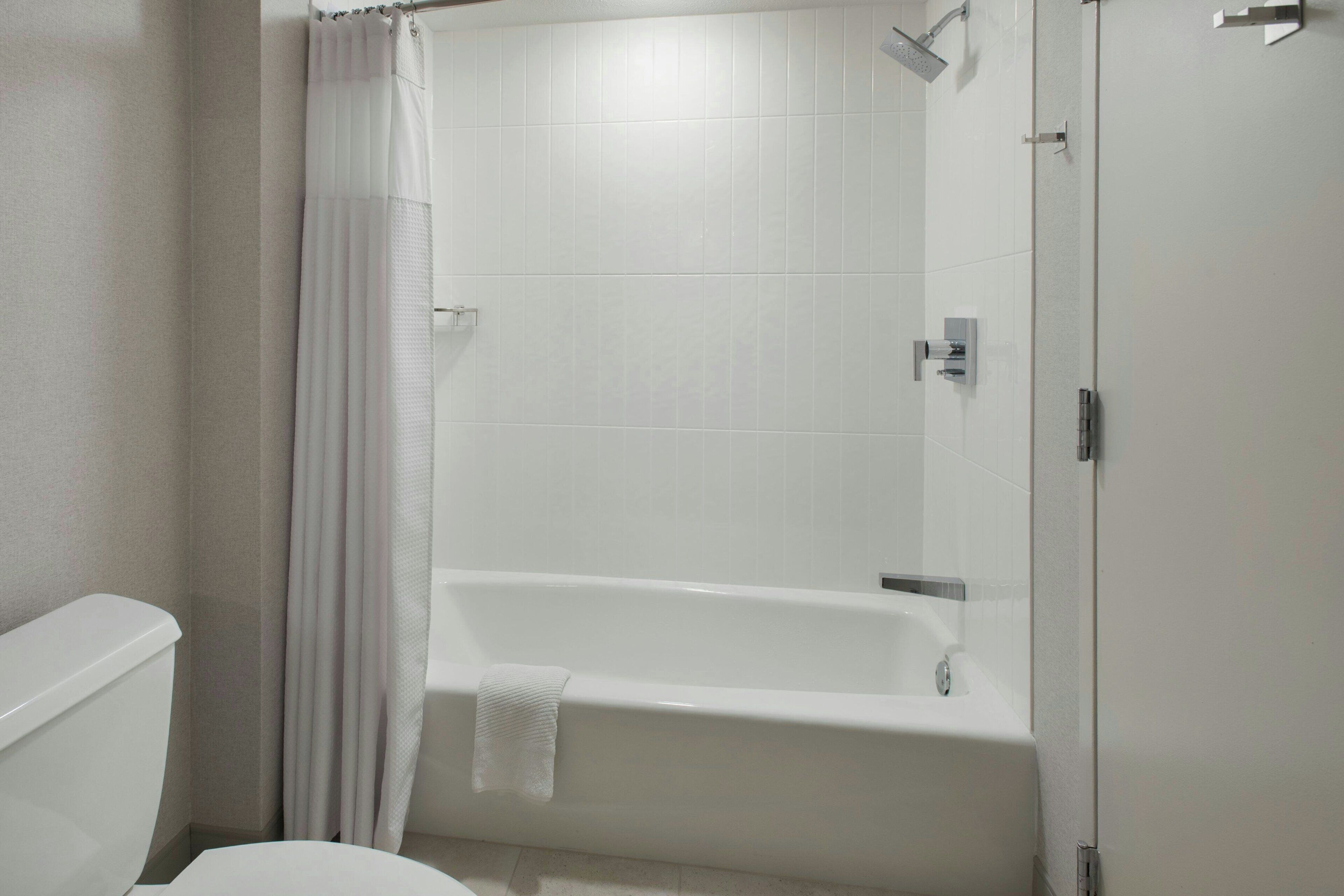 Un baño con una bañera blanca, un inodoro y una cortina de ducha.