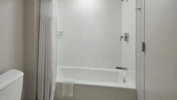 Un baño con una bañera blanca, un inodoro y una cortina de ducha.