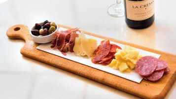 A wooden board with various cured meats, cheese, and olives, accompanied by a bottle of wine.