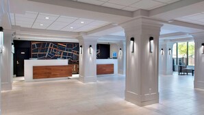Un vestíbulo amplio con mostrador de recepción, iluminación moderna y un piso limpio de baldosas.