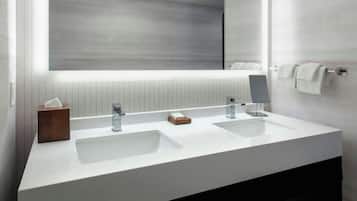 A modern bathroom with two sinks, a large mirror, and a towel rack.
