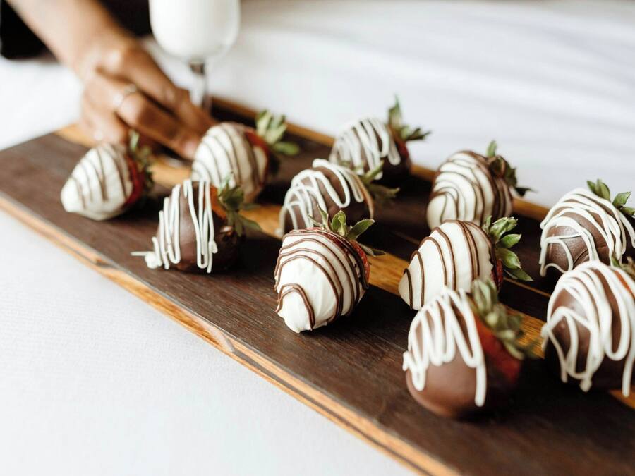 A tray of chocolate-covered strawberries on a wooden board.