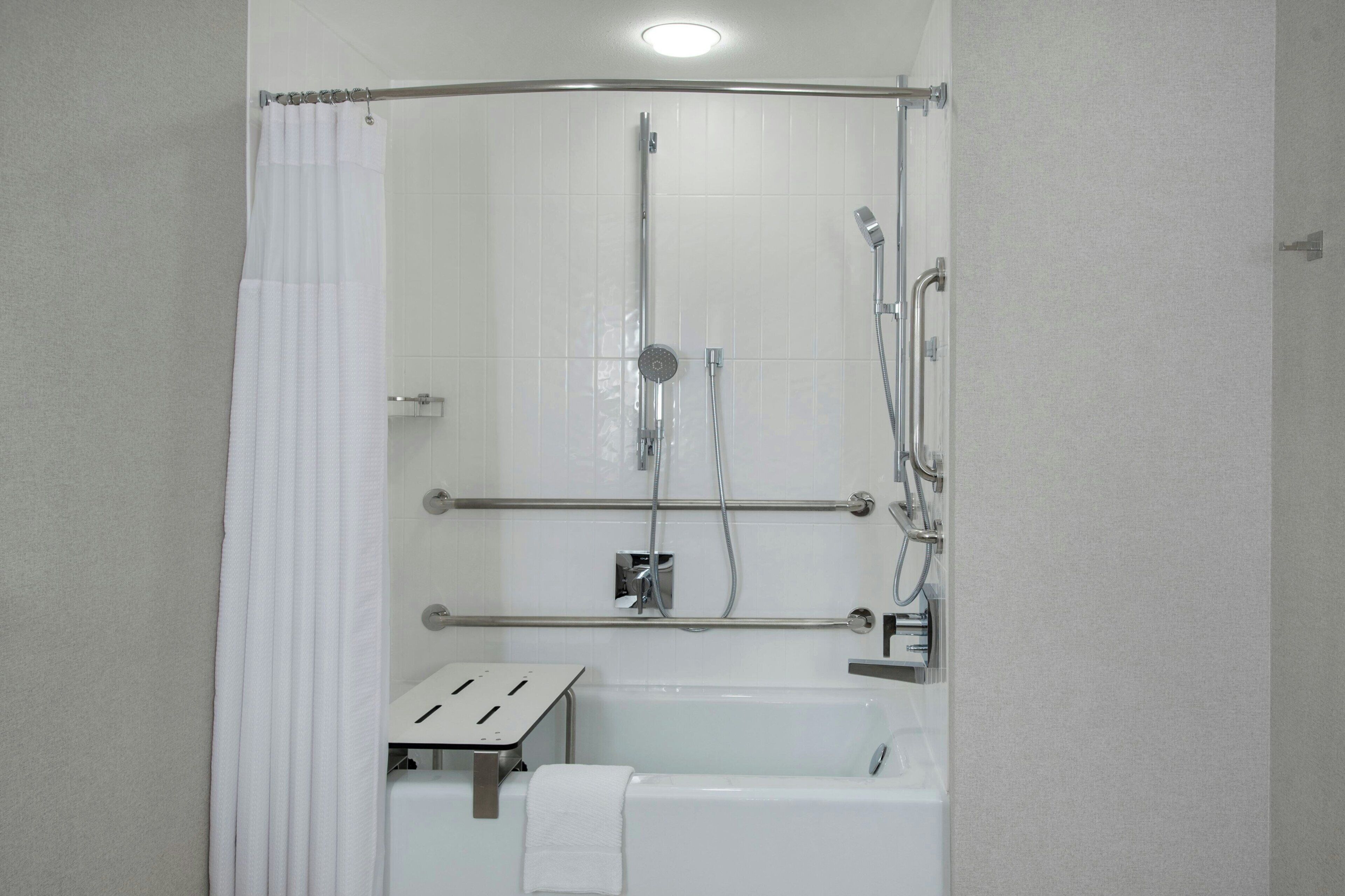 Un espacio de ducha con puerta de vidrio, una bañera y un perchero para toallas.
