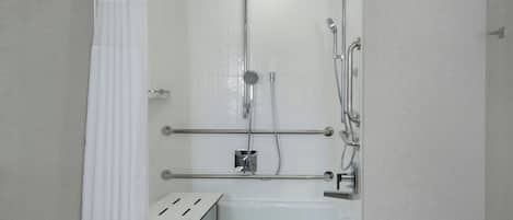Un espacio de ducha con puerta de vidrio, una bañera y un perchero para toallas.