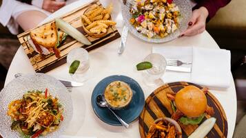 A table with various dishes including a burger, a salad, and a bowl of soup.