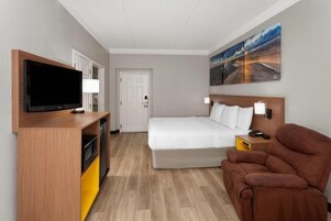 A hotel room with a bed, a TV, a desk, and a chair.