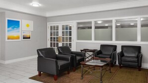 A room with four black leather chairs, a glass-top coffee table, and a patterned rug. - Days Inn & Suites by Wyndham Arlington Heights (Arlington Heights)
