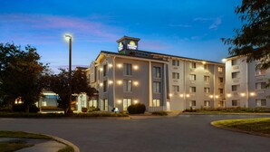 A multi-story hotel with a prominent 'Days Inn' sign, a well-lit entrance, and a parking area. - Days Inn & Suites by Wyndham Arlington Heights (Arlington Heights)