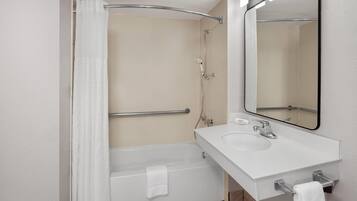 A modern bathroom with a bathtub, a shower, a sink, and a mirror.