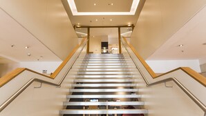 Eine moderne Treppe mit Holzwangen und einer Glaseinfassung, die zu einem hellen Innenraum führt.