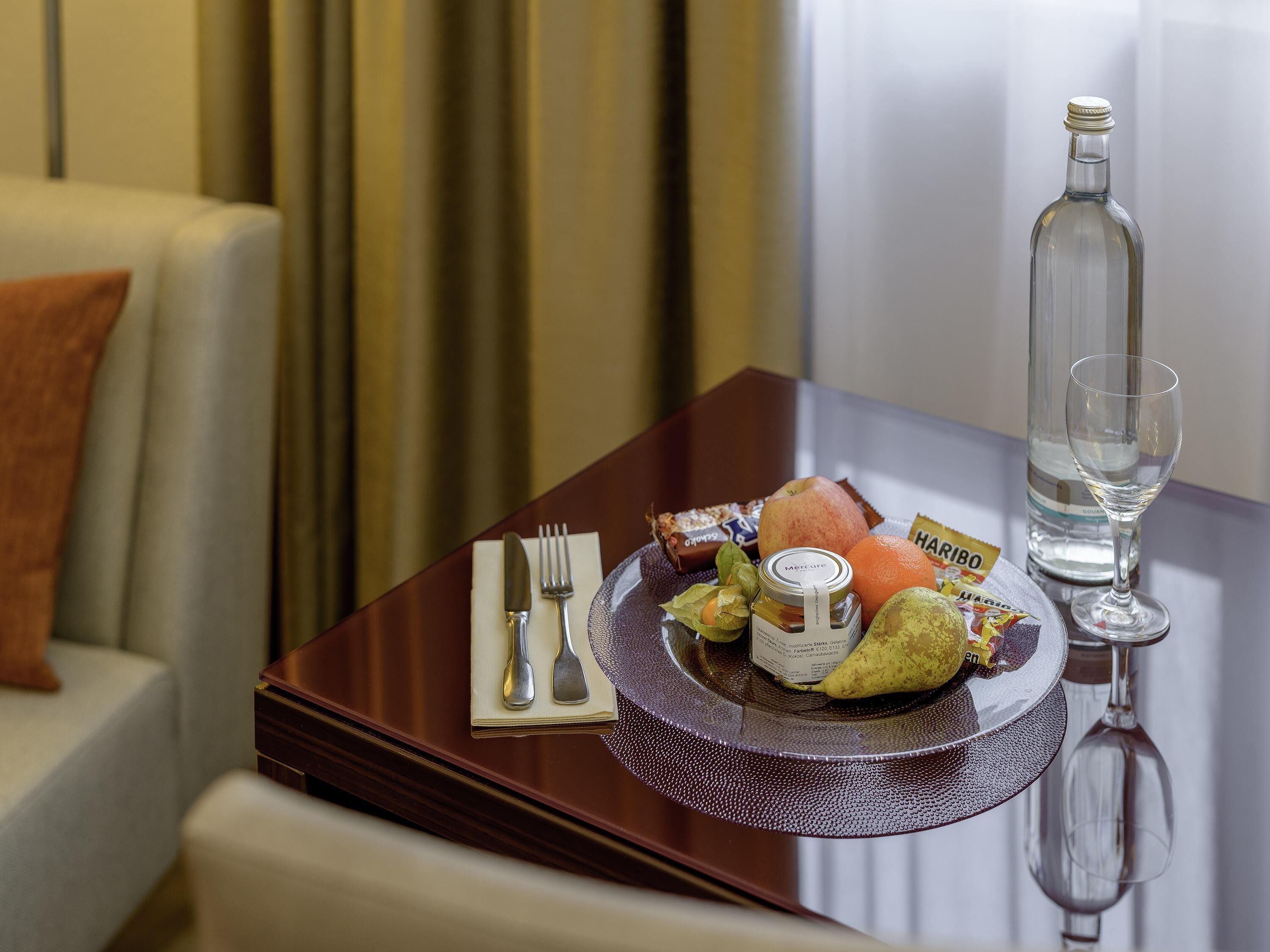 A dining table with a plate of food, a bottle, a glass, and cutlery.