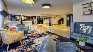 Eine moderne Hotelhalle mit Rezeption, Sitzgelegenheiten und einer Treppe.