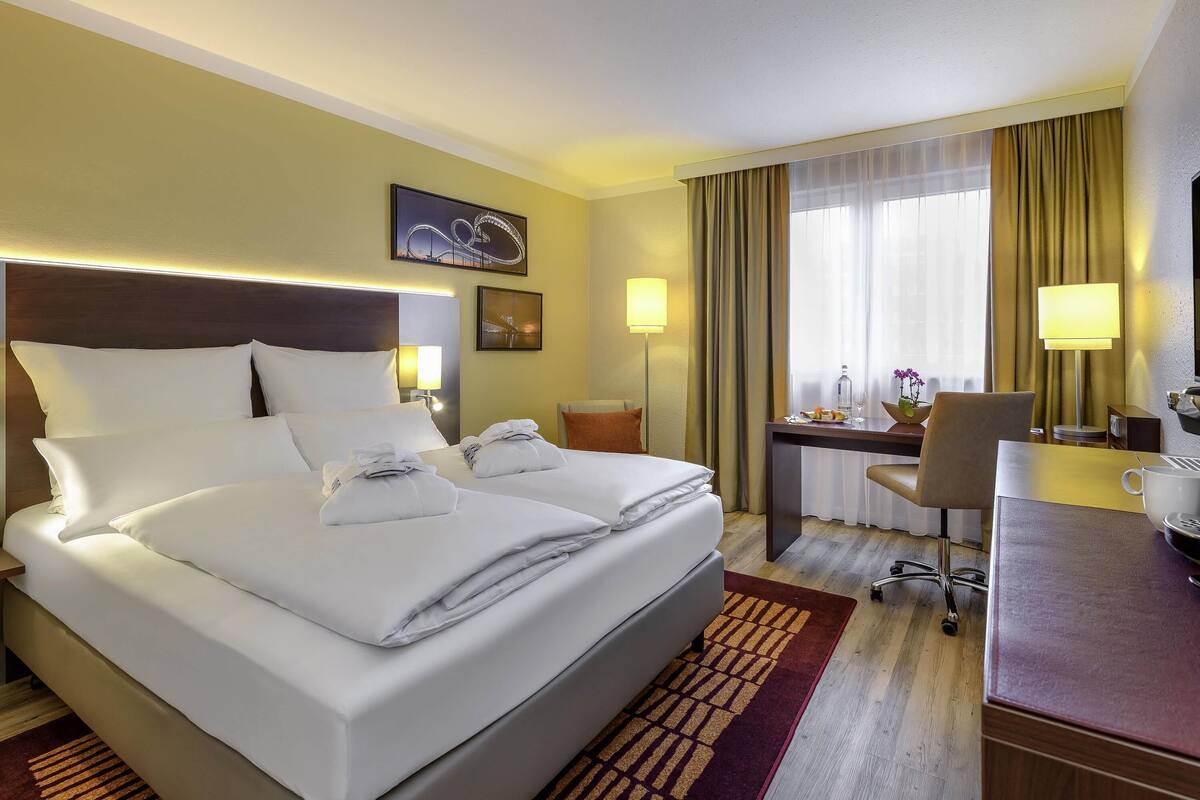 Een hotelkamer met een groot bed, een bureau, een stoel en een lamp.