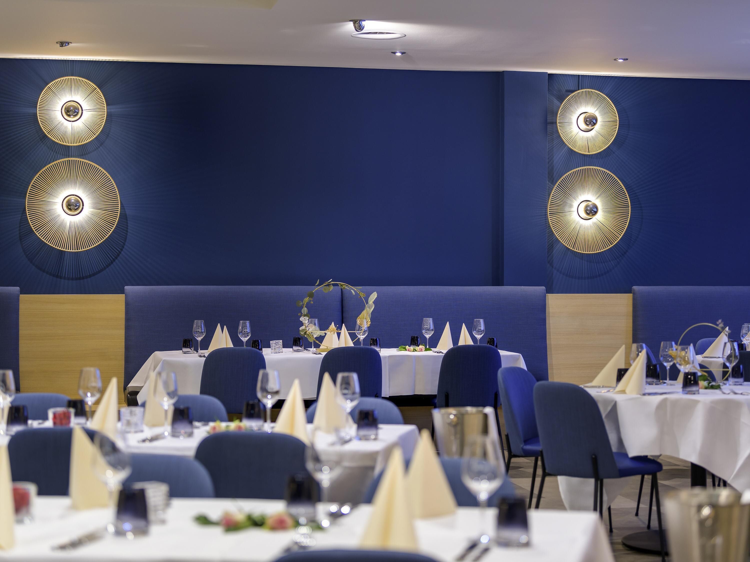 Un restaurante con mesas preparadas para comer, que presenta una decoración azul y paneles decorativos en las paredes.