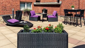 Ein Patio mit Korbmöbeln, darunter Stühle und eine Couch, sowie einem kleinen Tisch.
