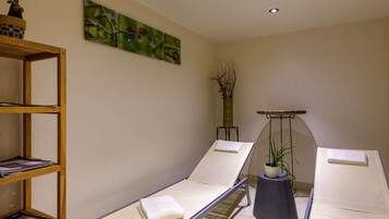 Relax in a serene spa room with reclining chairs, a bookshelf, and a beautiful wall art.
