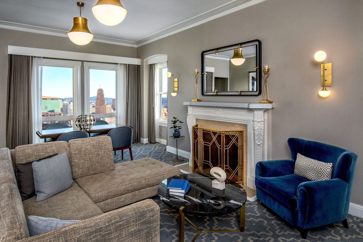 A living room with a sofa, armchair, fireplace, and city view.