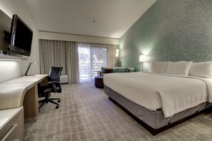A hotel room with a bed, desk, chair, and a television.