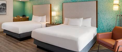 A hotel room with two beds, a nightstand, a chair, and a wall-mounted lamp.