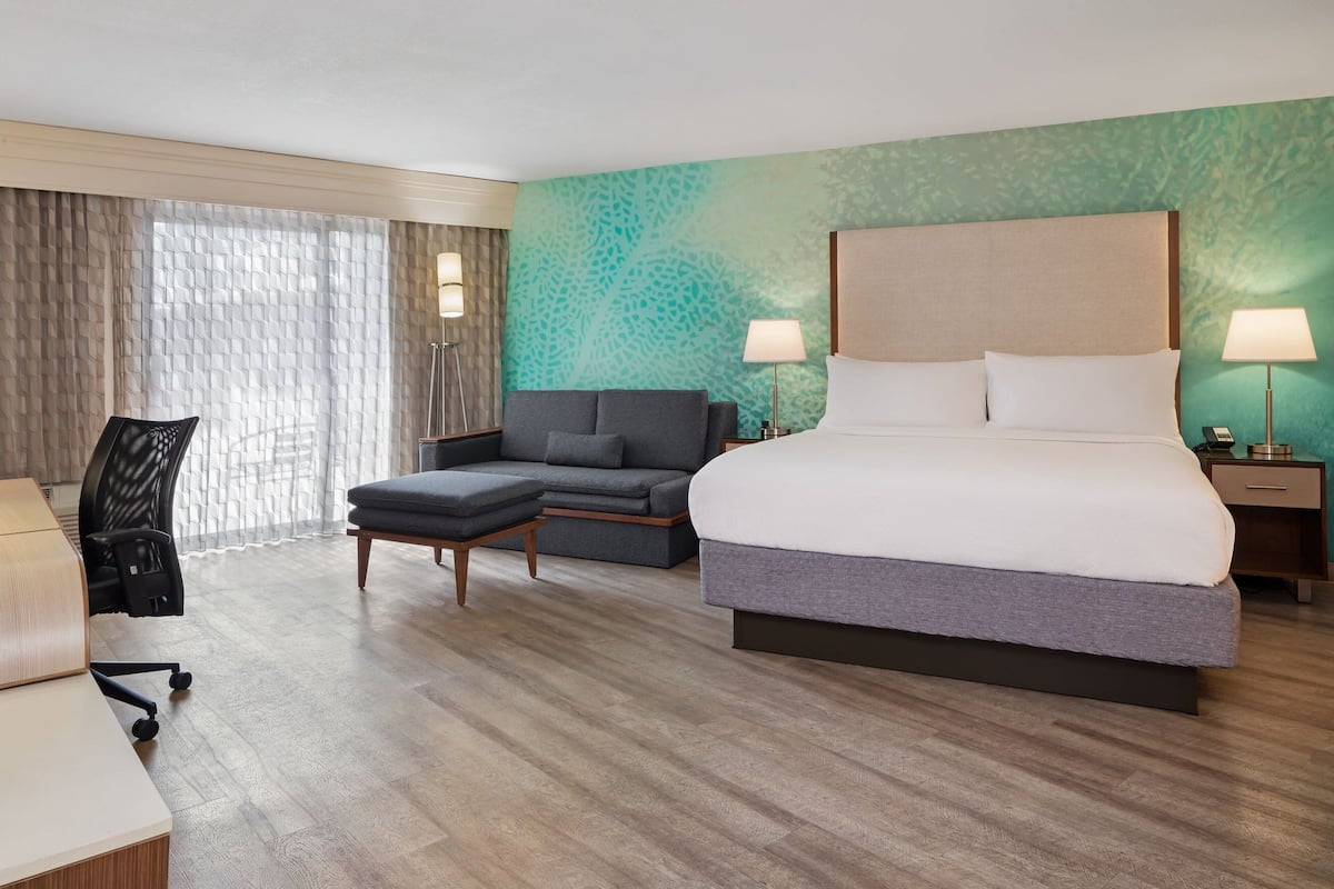 A hotel room with a large bed, a sofa, a desk, and a chair.