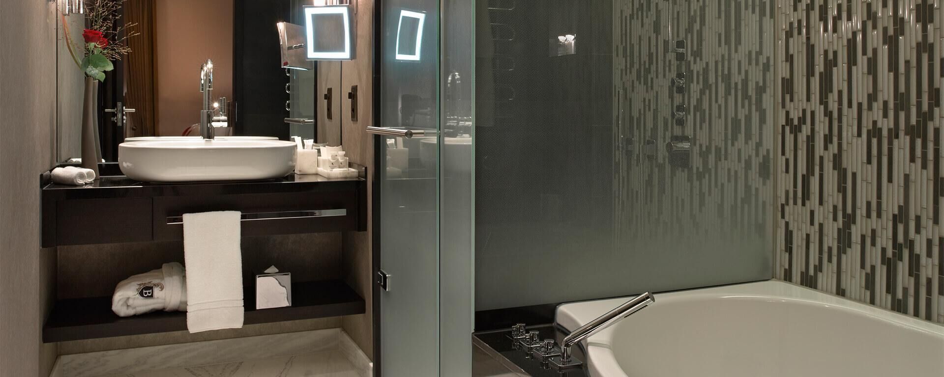 A modern bathroom with a large white bathtub, a round sink, and a glass-enclosed shower area.
