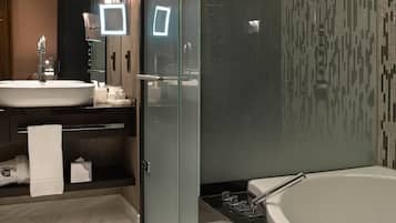 A modern bathroom with a large white bathtub, a round sink, and a glass-enclosed shower area.