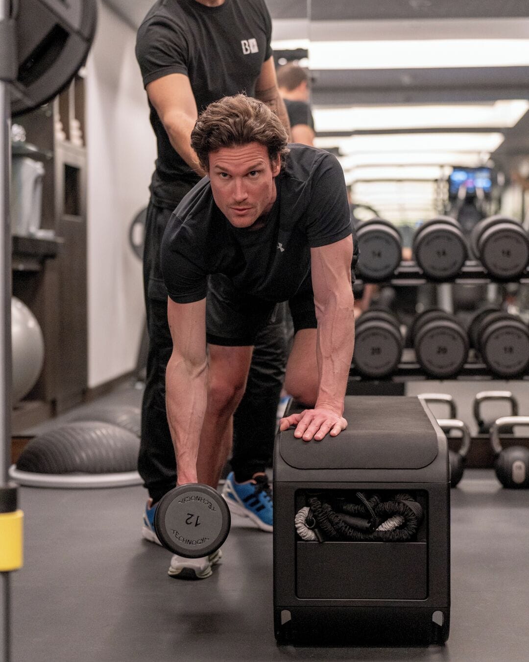 Ein Fitnessraum mit Krafttrainingsgeräten, darunter Kurzhanteln und eine Trainingsbank.