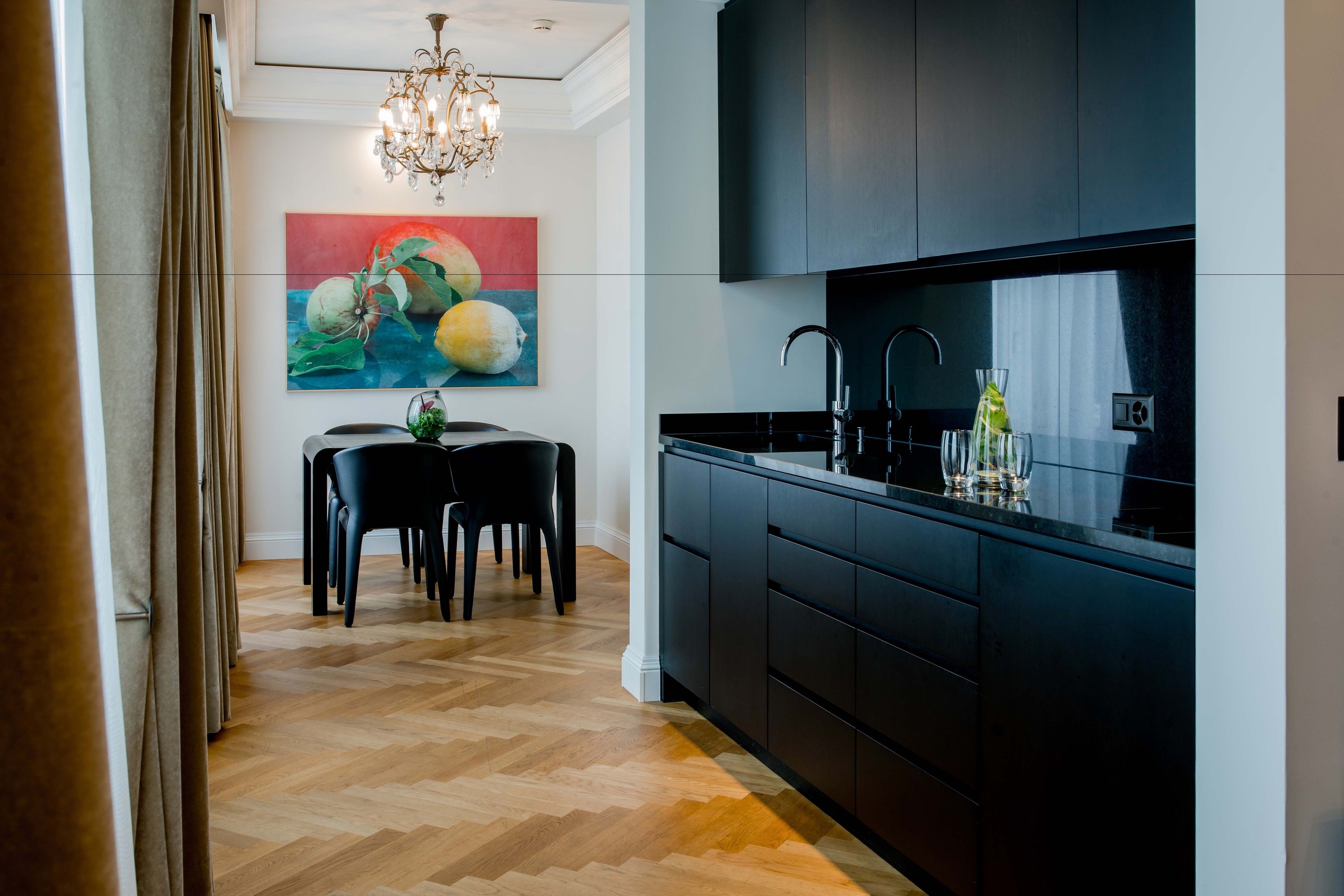 Une cuisine moderne avec des meubles de couleur sombre, un plan de travail noir et un lustre.