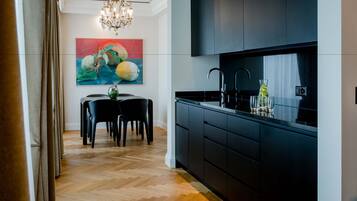 Une cuisine moderne avec des meubles de couleur sombre, un plan de travail noir et un lustre.