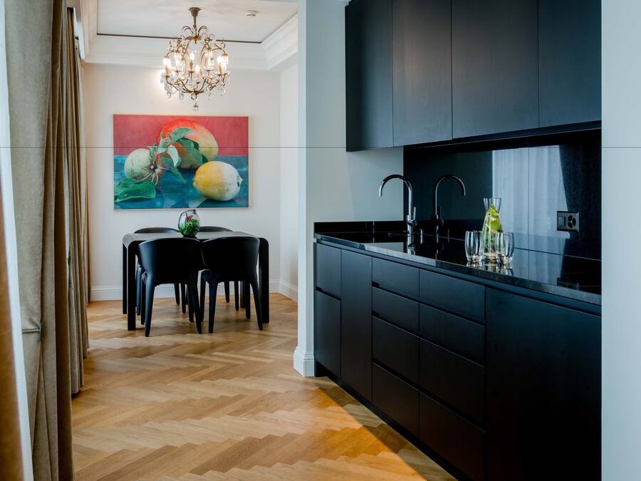 Une cuisine moderne avec des meubles de couleur sombre, un plan de travail noir et un lustre.