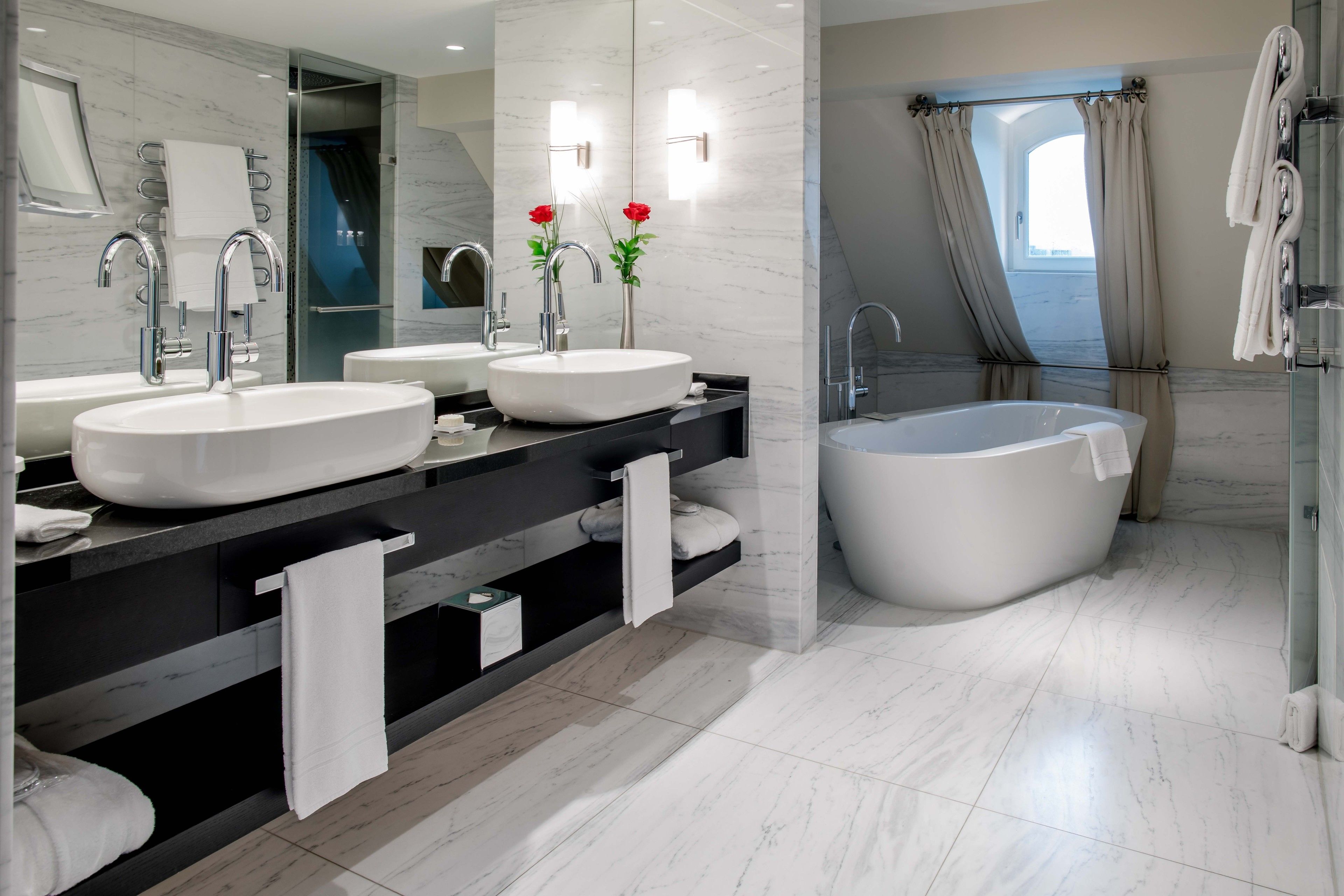 Une salle de bain moderne avec deux lavabos, une grande baignoire et une cabine de douche en verre.