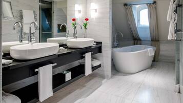 Une salle de bain moderne avec deux lavabos, une grande baignoire et une cabine de douche en verre.