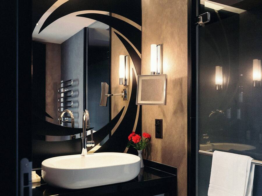 A modern bathroom with a round mirror, a white sink, and a glass shower enclosure.