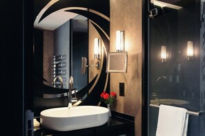 A modern bathroom with a round mirror, a white sink, and a glass shower enclosure. - Hotel Schweizerhof Bern & Spa (Bern)