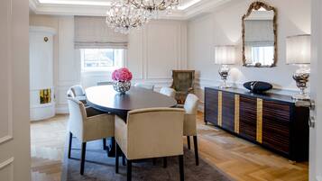 A dining area with a round table, chairs, a chandelier, a mirror, and a cabinet.