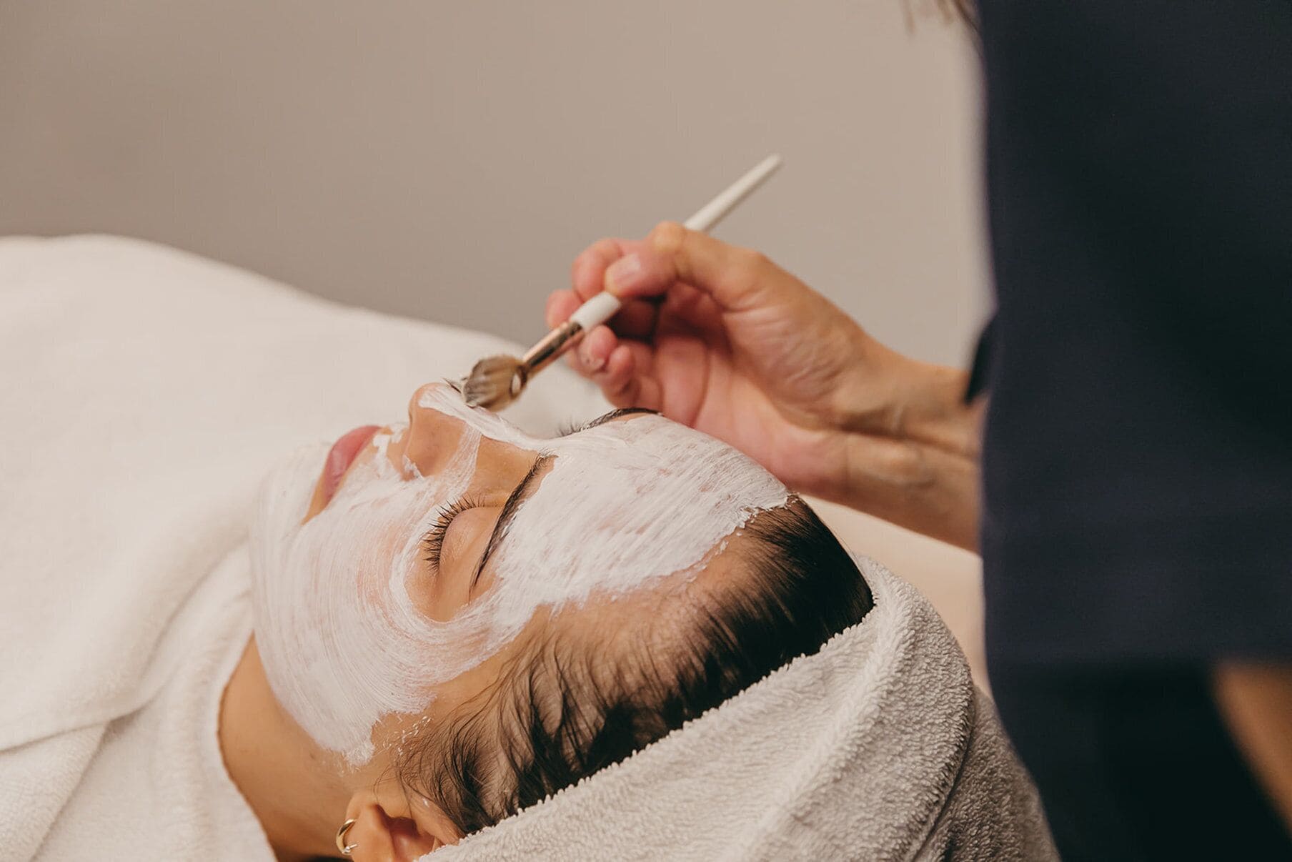 A person receiving a facial treatment with a brush.