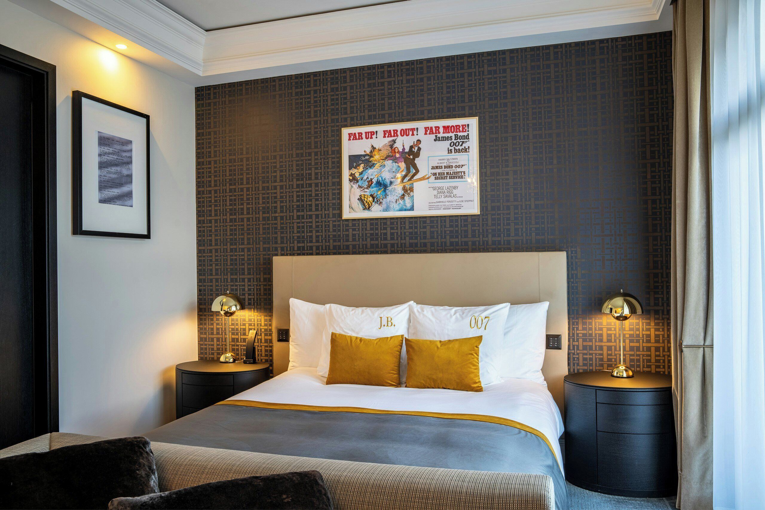 A hotel room with a large bed, two bedside tables with lamps, a framed picture on the wall, and a poster above the bed.