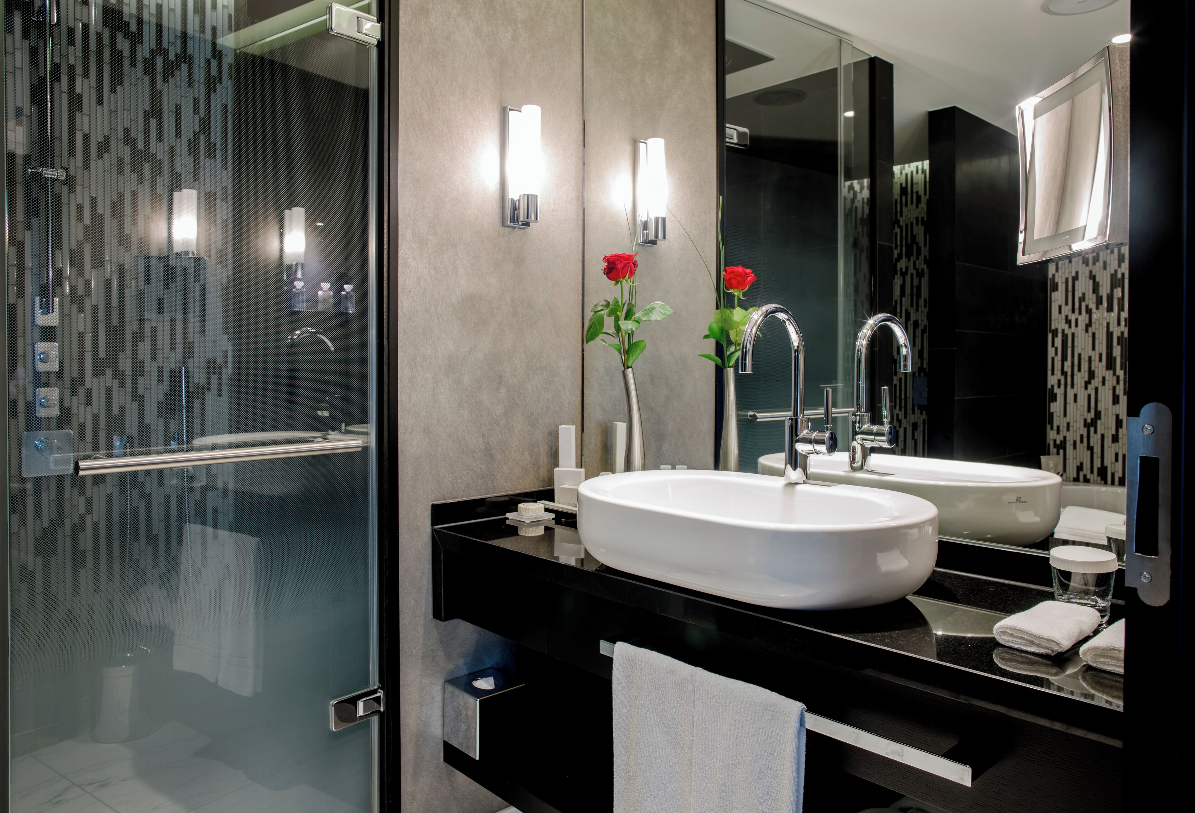 Une salle de bain moderne avec deux lavabos, une douche à l’italienne en verre et un grand miroir.