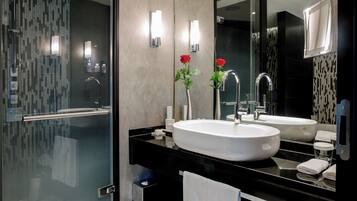 Une salle de bain moderne avec deux lavabos, une douche à l’italienne en verre et un grand miroir.