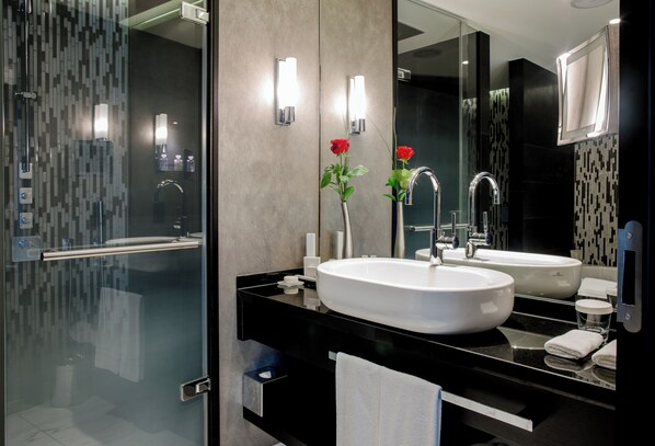 Un baño moderno con dos lavamanos, una cabina de ducha de vidrio y un espejo grande.