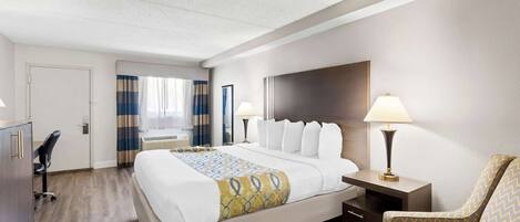 A hotel room with a large bed, a desk, a chair, and a TV.