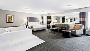 A modern hotel bathroom with a large bathtub, a sofa, a chair, and a mirror. - Best Western Naperville Inn (Naperville)