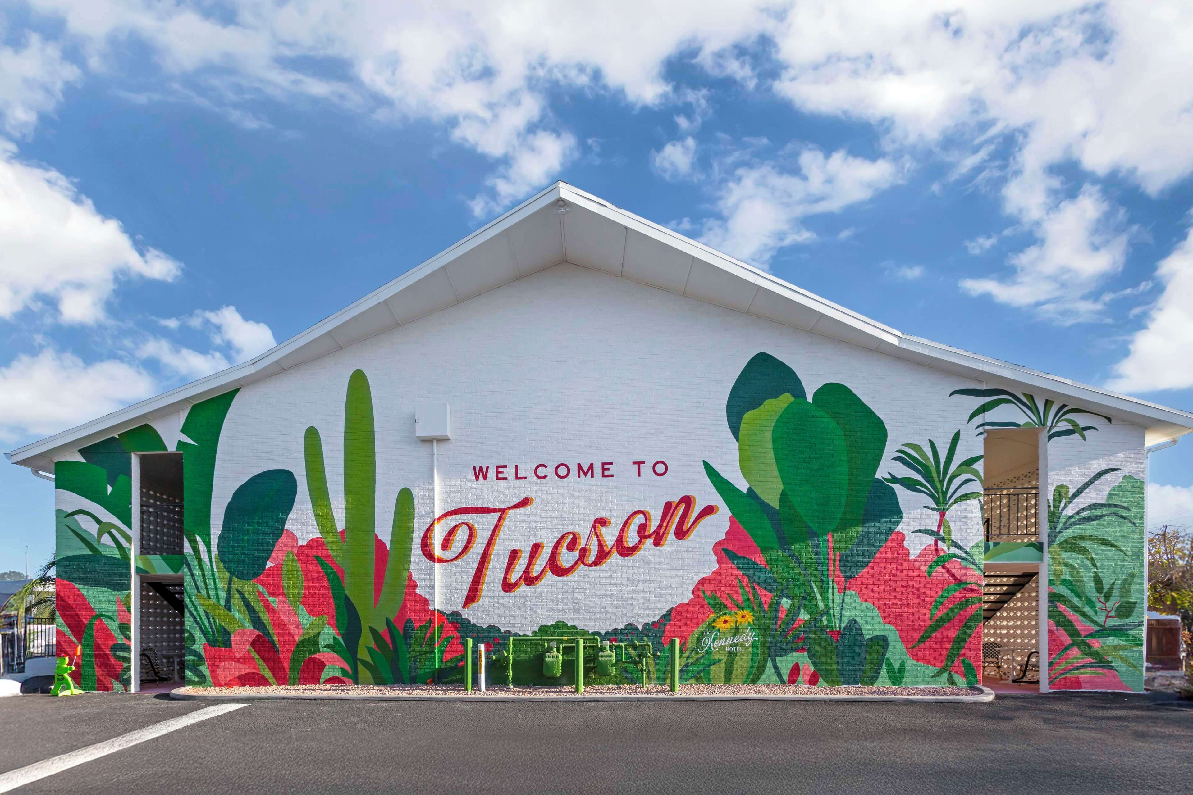 A building with a mural welcoming visitors to Tucson, featuring desert flora.