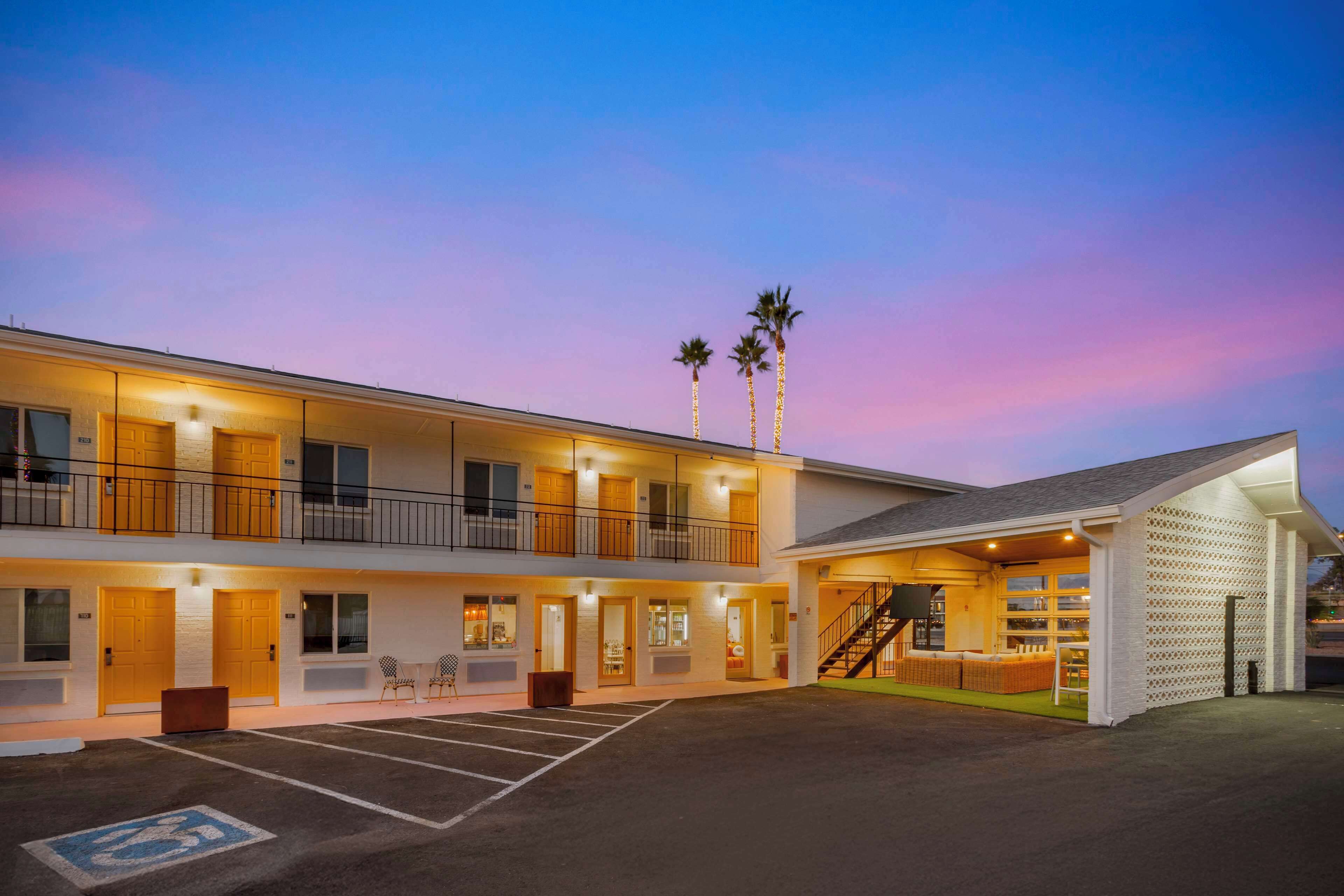 A motel with a two-story structure, a covered parking area, and a staircase leading to the upper level.
